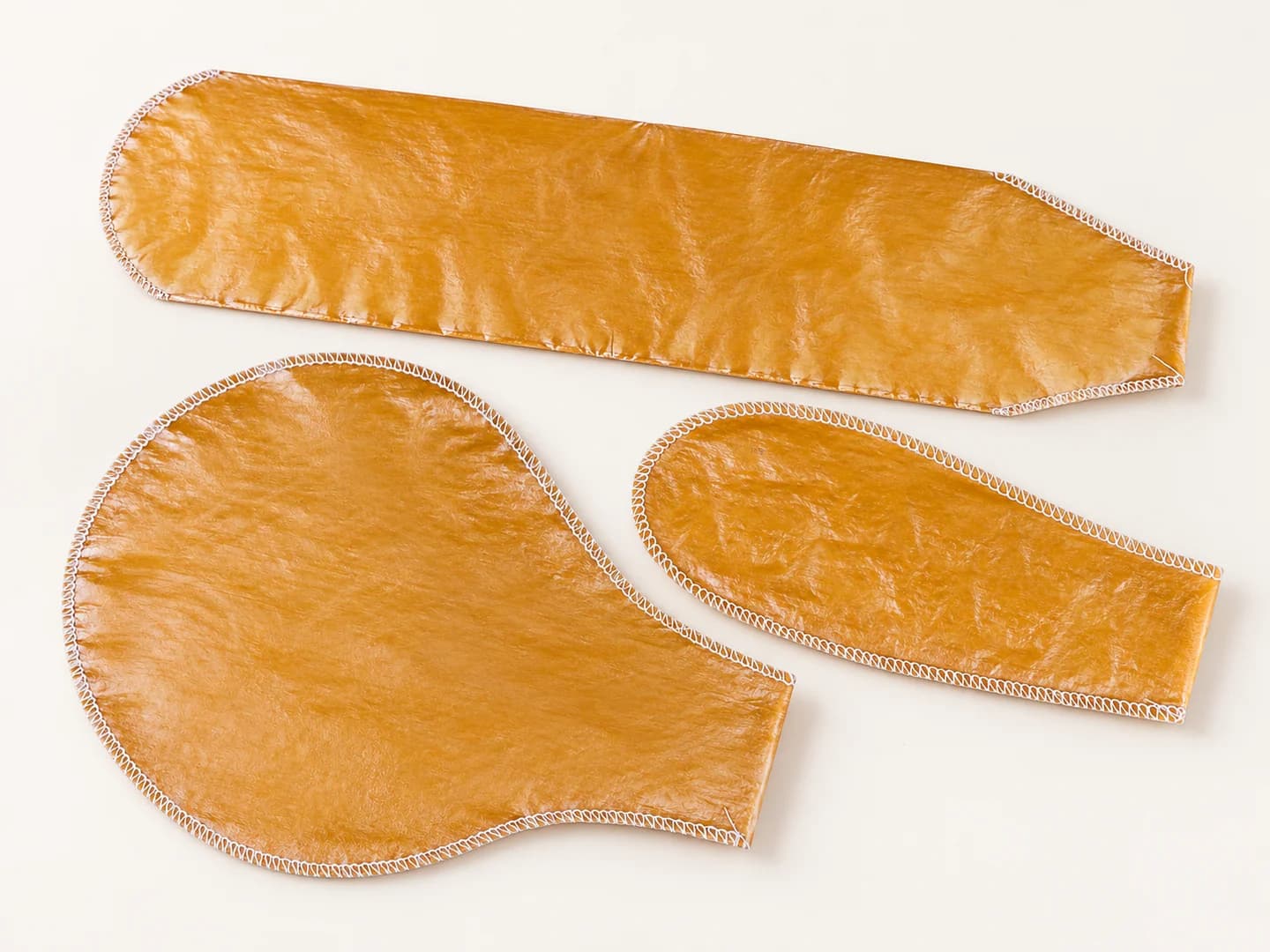 Illustration of three amber sewn casings with distinct shapes and white stitched edges.
